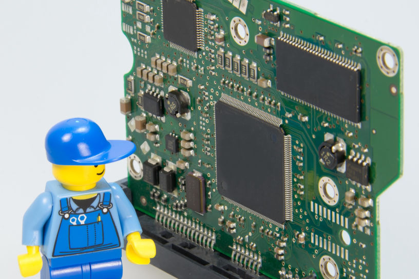 lego man standing next to an electronic circuit board